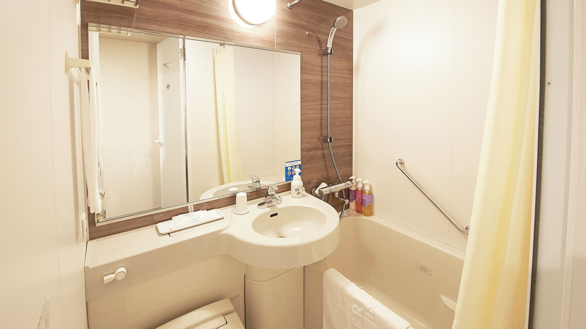 A bathroom with a sink, mirror, shower, and towel rack.