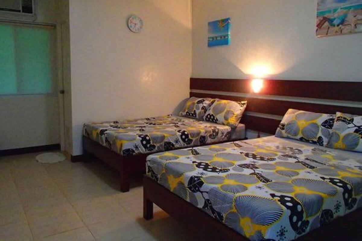 Una habitación con dos camas, un reloj de pared y un cuadro.