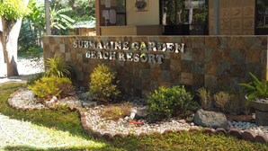 Opastekyltti, jossa lukee ”Submarine Garden Beach Resort”, ja sen yhteydessä on kivimuuri sekä maisemoitu puutarha.