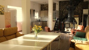 Ein geräumiges Wohnzimmer mit einem weißen Tisch und gelben Stühlen, eine Küche mit Steinwänden und einer schwarzen Wendeltreppe.