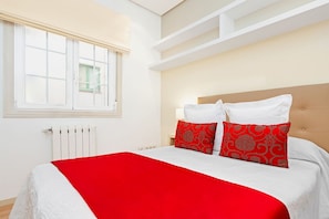 Un dormitorio con cama, ventana y radiador.