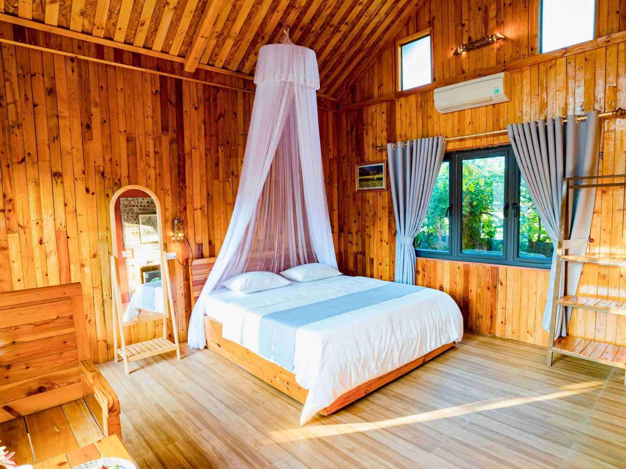 A wooden cabin bedroom with a canopy bed, a small window, and a wooden dresser.