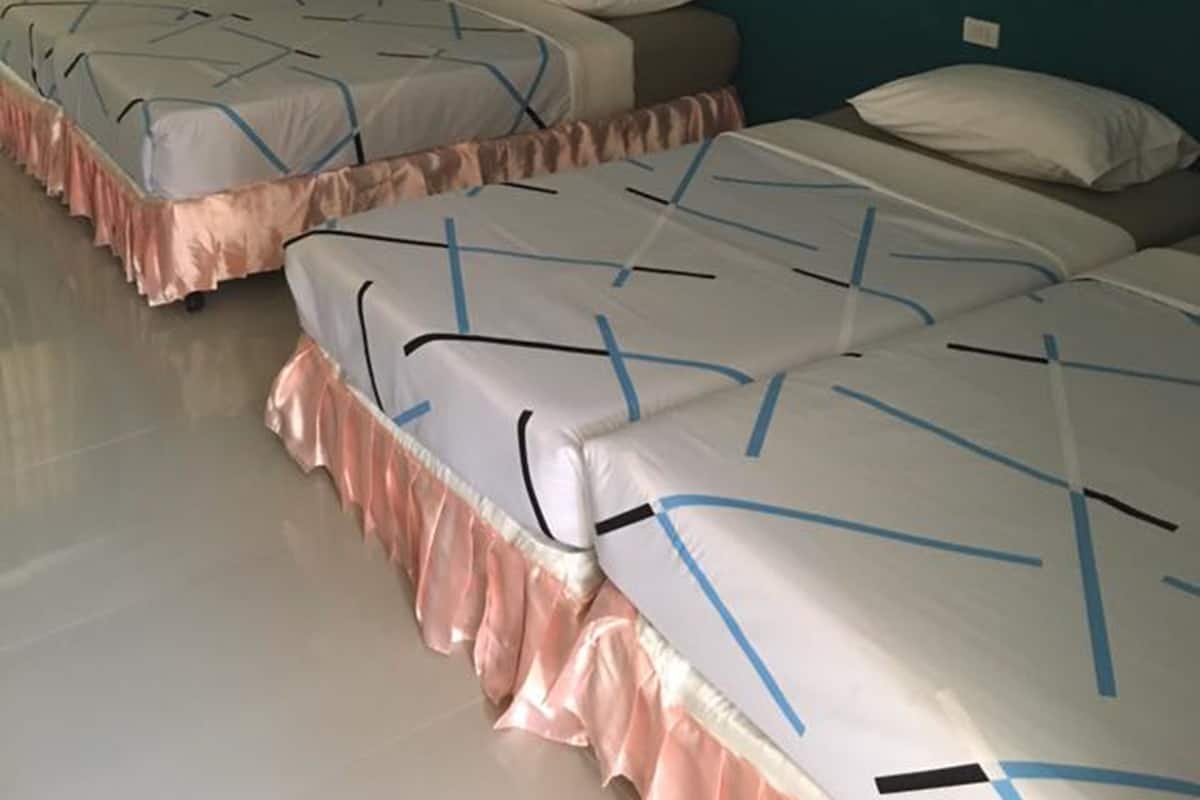 Een hotelkamer met twee bedden, een muur in teal-kleur en een houten deur.