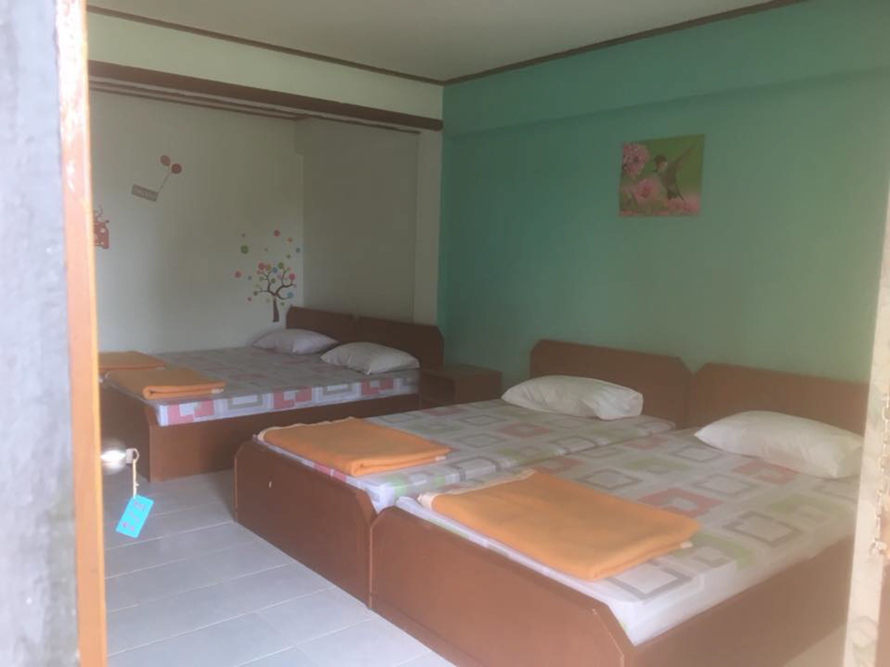 A room with two beds, a small table, and a wall decoration.