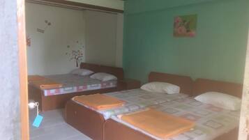 A room with two beds, a small table, and a wall decoration.