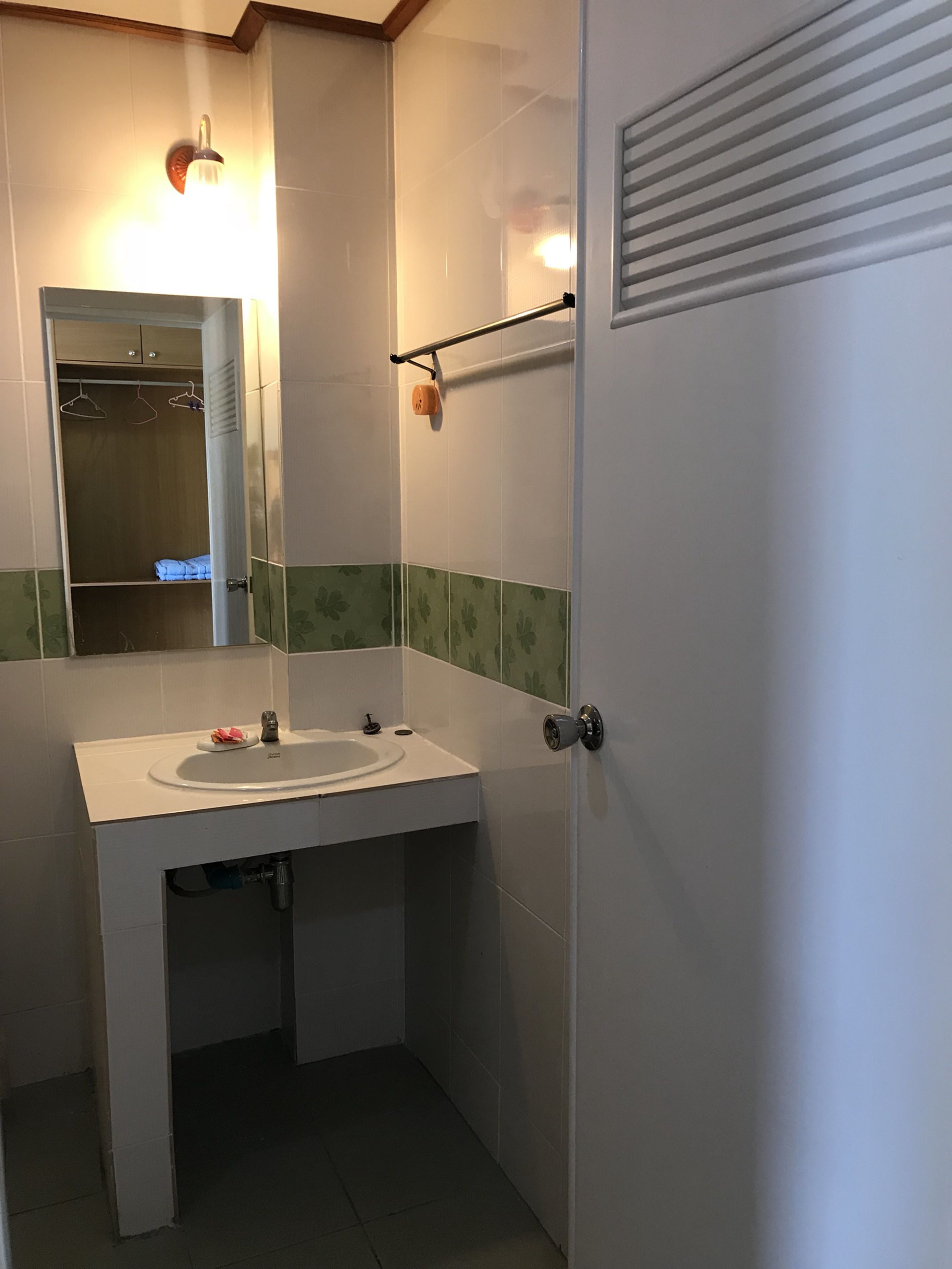 A bathroom with a white sink, a mirror, and a towel rack.