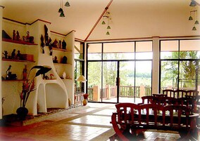 Una habitación espaciosa con un ventanal grande, una silla blanca y un banco de madera.