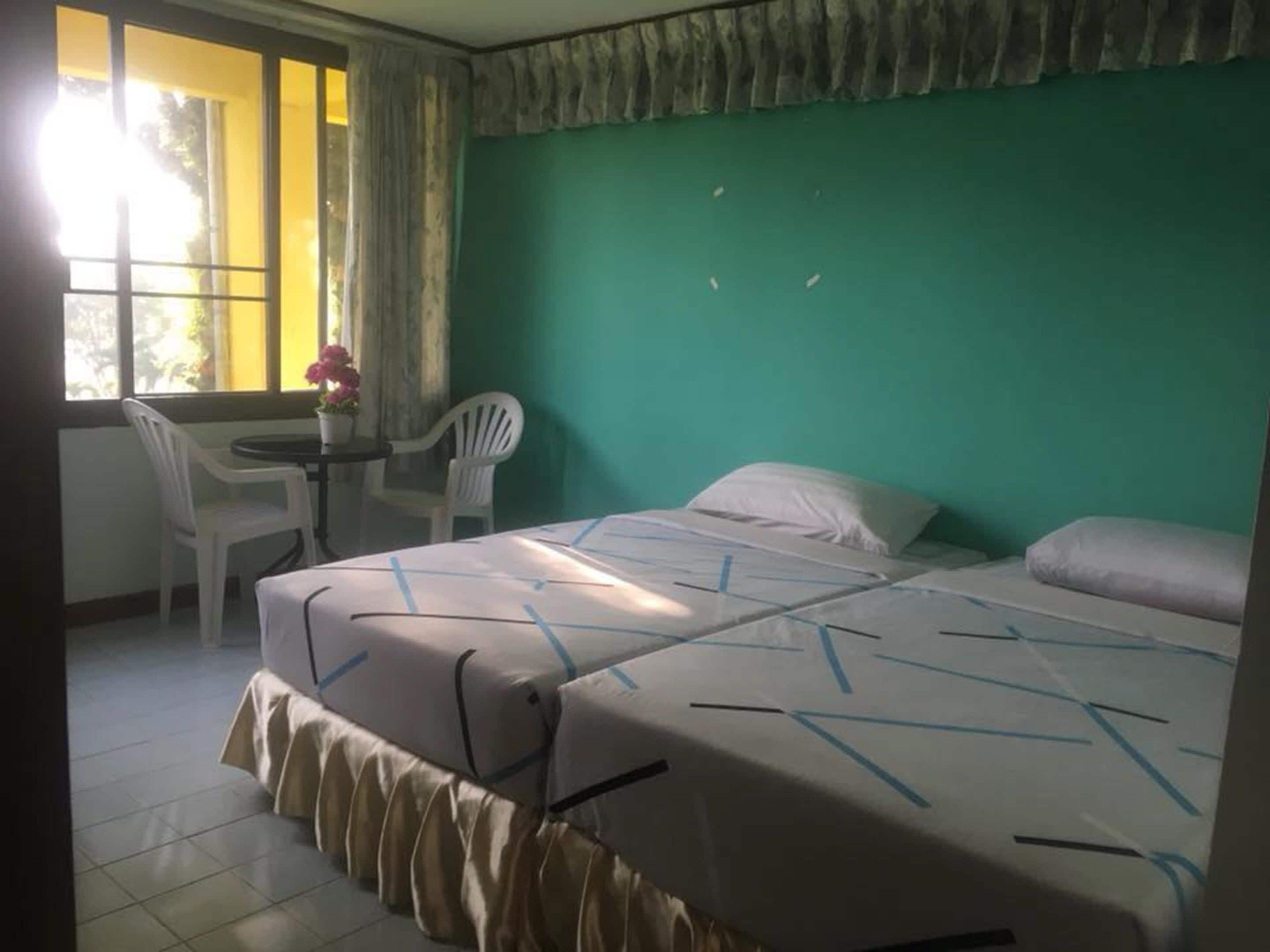 Una habitación con una cama, una pequeña mesa con sillas y una ventana con cortinas.