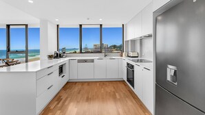 Una cocina moderna con una isla grande, electrodomésticos de acero inoxidable y vista al océano.