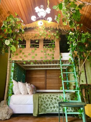 A bunk bed with a ladder, a small table, and a couch with pillows. - Bleu Verde i am colors (Gili Trawangan)