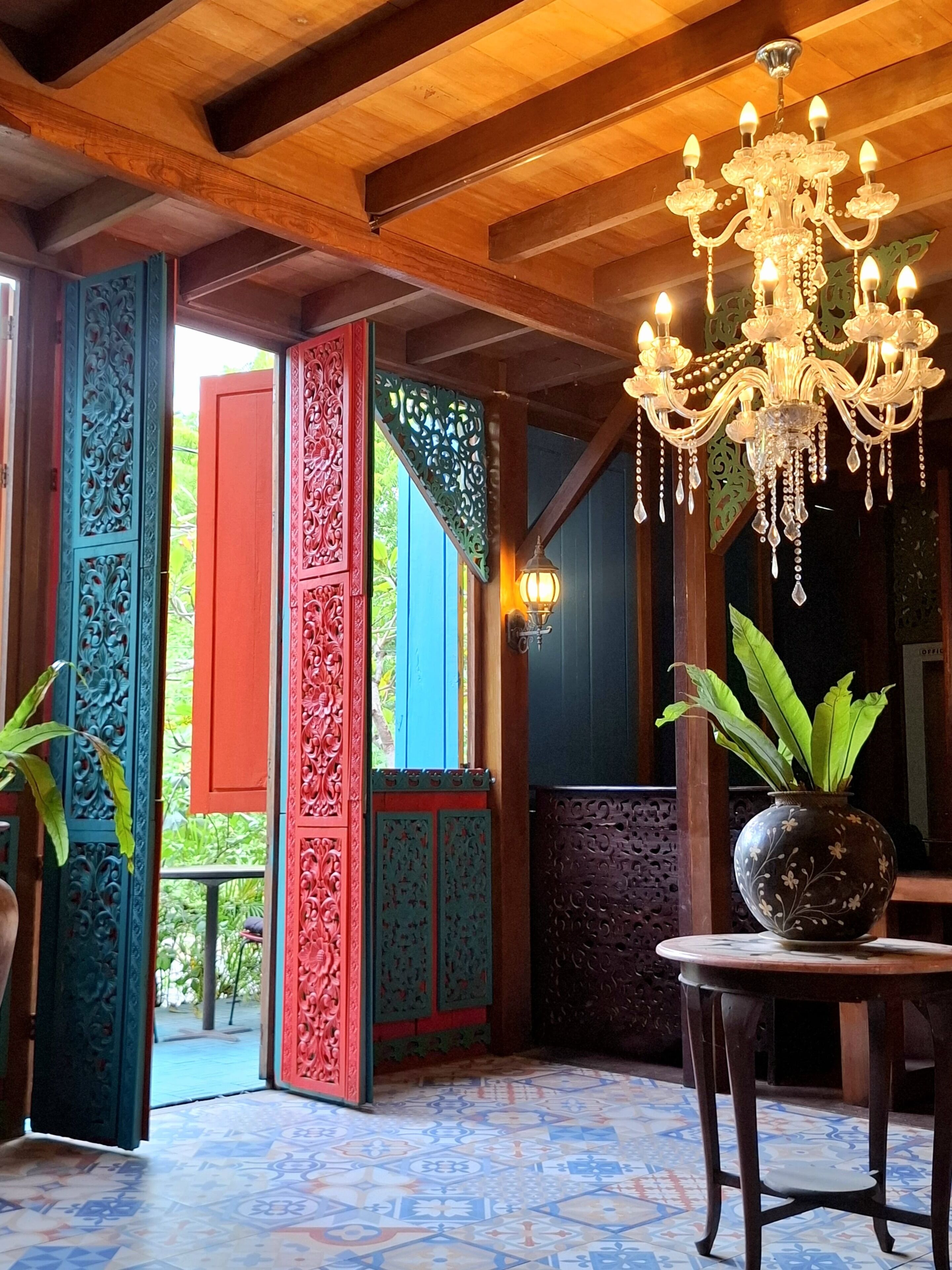 A room with a chandelier, a table with a potted plant, and a patterned floor.