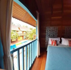 Een kamer met balkon, een bed met kussens en een hoofdbord met patroon.