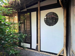 A traditional Japanese building with a tatami mat interior, a bamboo structure, and a view of a cityscape through a circular window. - Bleu Verde i am colors (Gili Trawangan)