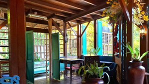 Un espace extérieur aménagé, abrité et doté de poutres en bois, d’une table, de chaises et de plantes en pot.