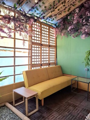 A room with a yellow sofa, a small table, a glass table, and a bamboo partition. - Bleu Verde i am colors (Gili Trawangan)