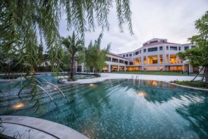 Et moderne hotel med swimmingpool, omgivet af palmer og en velplejet have.