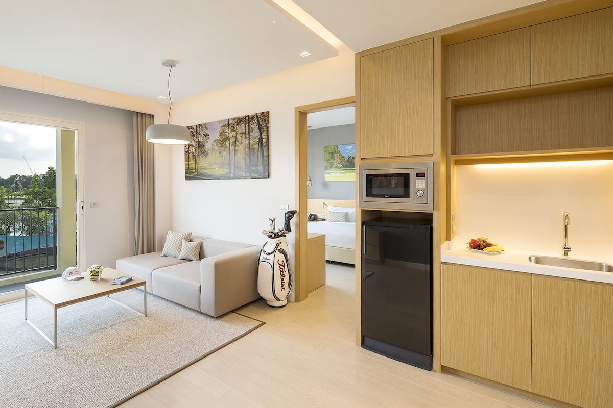 A modern apartment with a kitchen, a living area with a sofa, a dining table, and a large window.