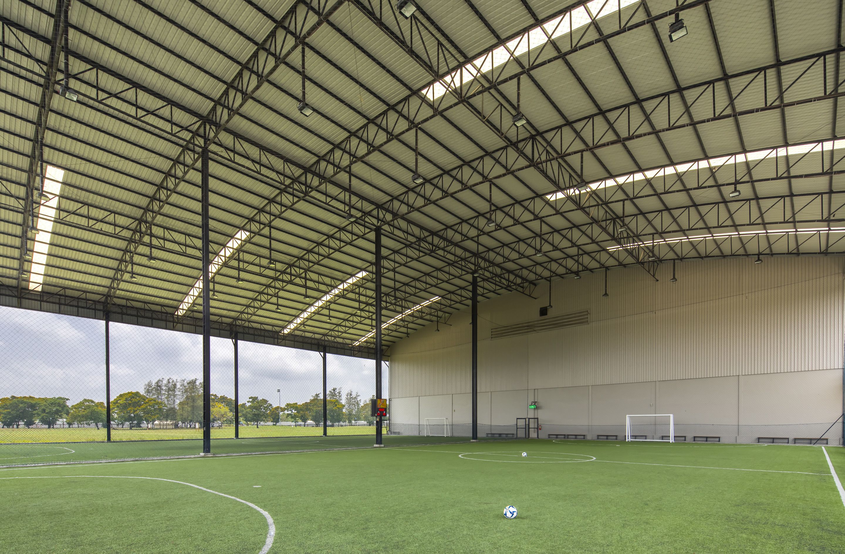 An indoor soccer field with a high ceiling and large windows.