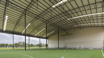 An indoor soccer field with a high ceiling and large windows.