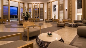 A spacious lobby with a modern design, featuring a mix of seating areas, a central round table, and traditional wooden partitions. - Eastin Thana City Golf Resort Bangkok (Bang Phli)