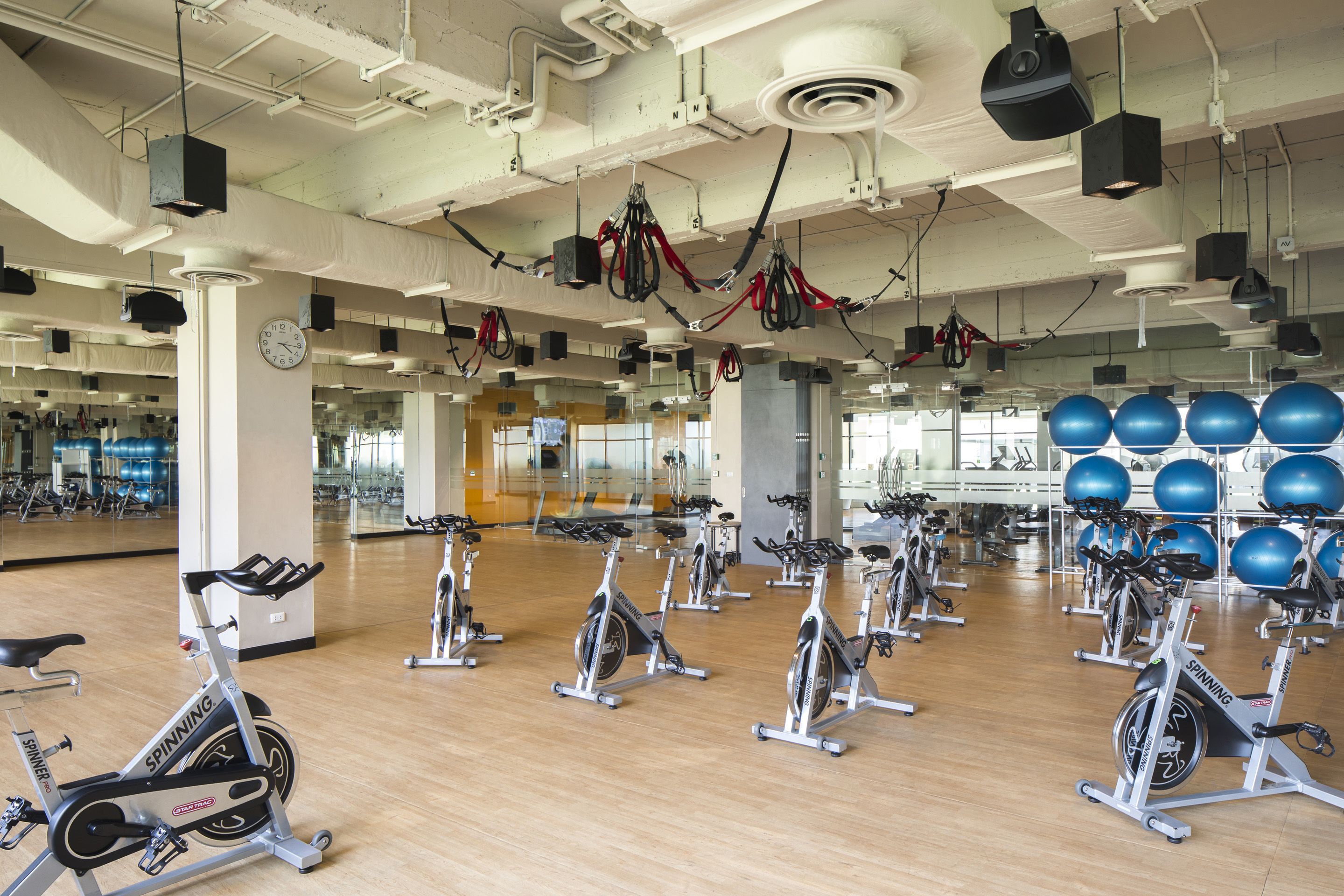 A gym with stationary bikes, exercise balls, and mirrors.