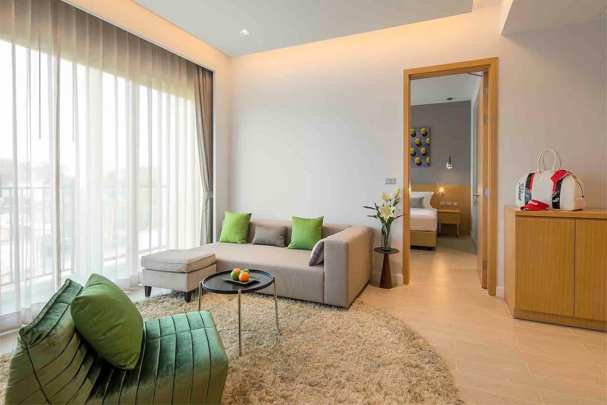 A modern living room with a sofa, a coffee table, and a view through large windows.