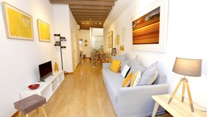 Uma sala de estar moderna com um sofá cinzento, piso de madeira e obras de arte nas paredes.