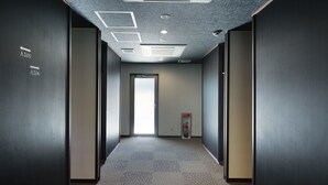 A hallway with directional signs, a fire extinguisher, and a door at the end. - Hotel Famitic Nikko (Nikko)
