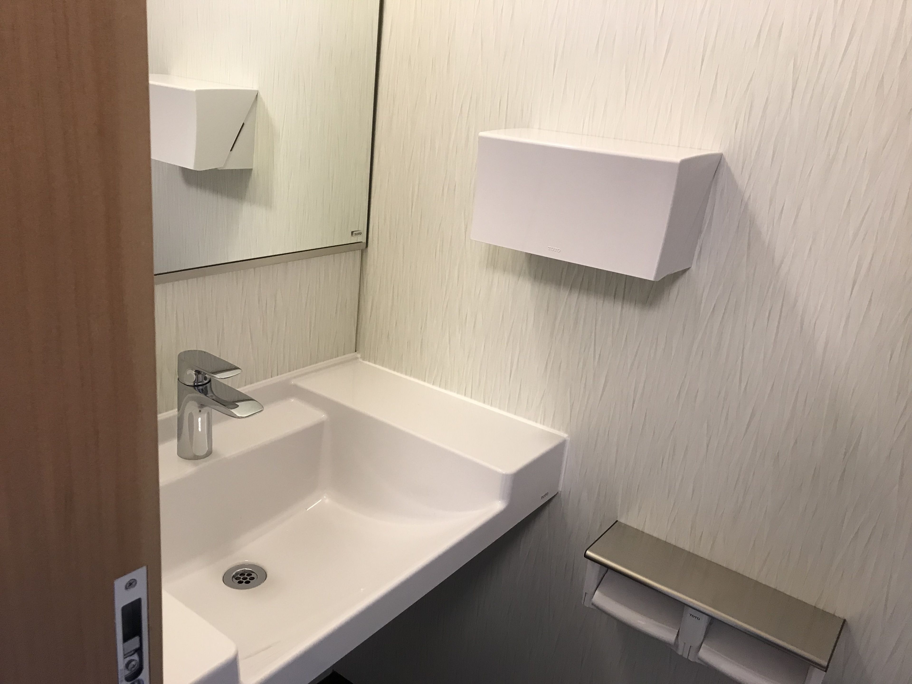 A bathroom with a white sink, a mirror, and a towel rack.