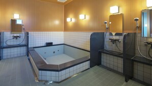 A modern bathroom with a large bathtub, separate shower areas, and tiled walls. - Hotel Famitic Nikko (Nikko)