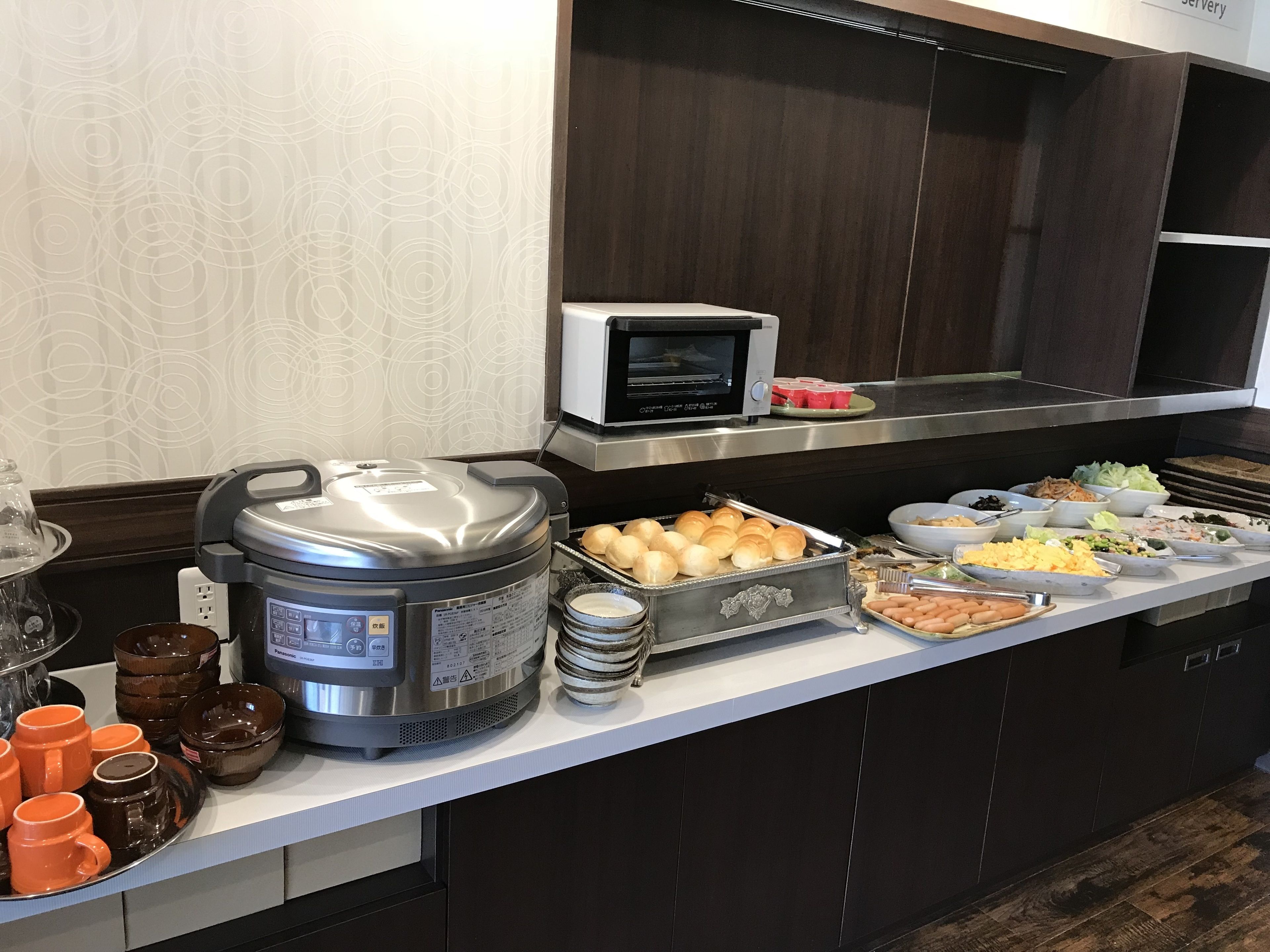 A buffet setup with a variety of food items, a coffee maker, and a microwave.