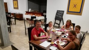 A dining area with tables and chairs, a chalkboard menu, and a kitchen in the background. - Vini Villa (Deniyaya)