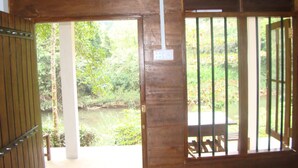 A wooden door with a metal gate, leading to an outdoor area with a bench and a table. - Vini Villa (Deniyaya)