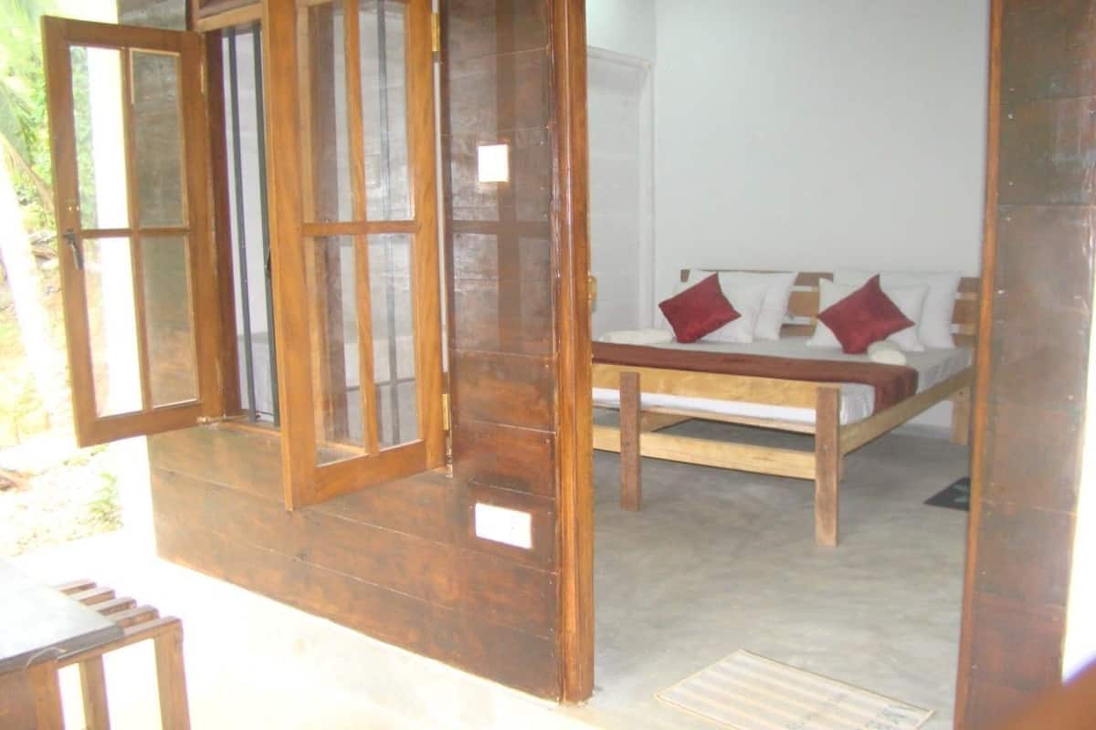 A room with a bed, a wooden door, and a small table.