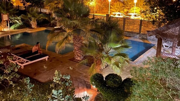 A nighttime view of a hotel pool area with palm trees and a lounge chair. - South Marina Fiorita house (Hurghada)