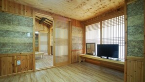 Et traditionelt japansk rum med tatamimåtter, shoji-skærme og et fjernsyn på et træstel.
