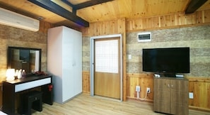 Een kamer met houten wanden en plafond, een witte kledingkast, een televisie en een klein raam.