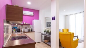 A modern kitchen with a wooden countertop, a built-in stove, and a white refrigerator. There is a yellow chair in the dining area and a sign that reads "Puerta del Sol".