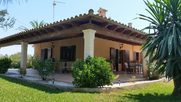 Un patio techado al aire libre con zona de comedor, una pérgola y vistas del paisaje circundante.