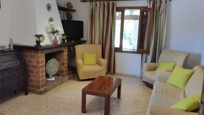 Una sala de estar con chimenea de ladrillo, dos sofás, una mesa de centro de madera y un televisor.