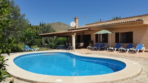 Una piscina con sillas de descanso y un porche cubierto.