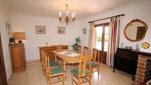 Un comedor con una mesa y sillas de madera, una araña y una chimenea.