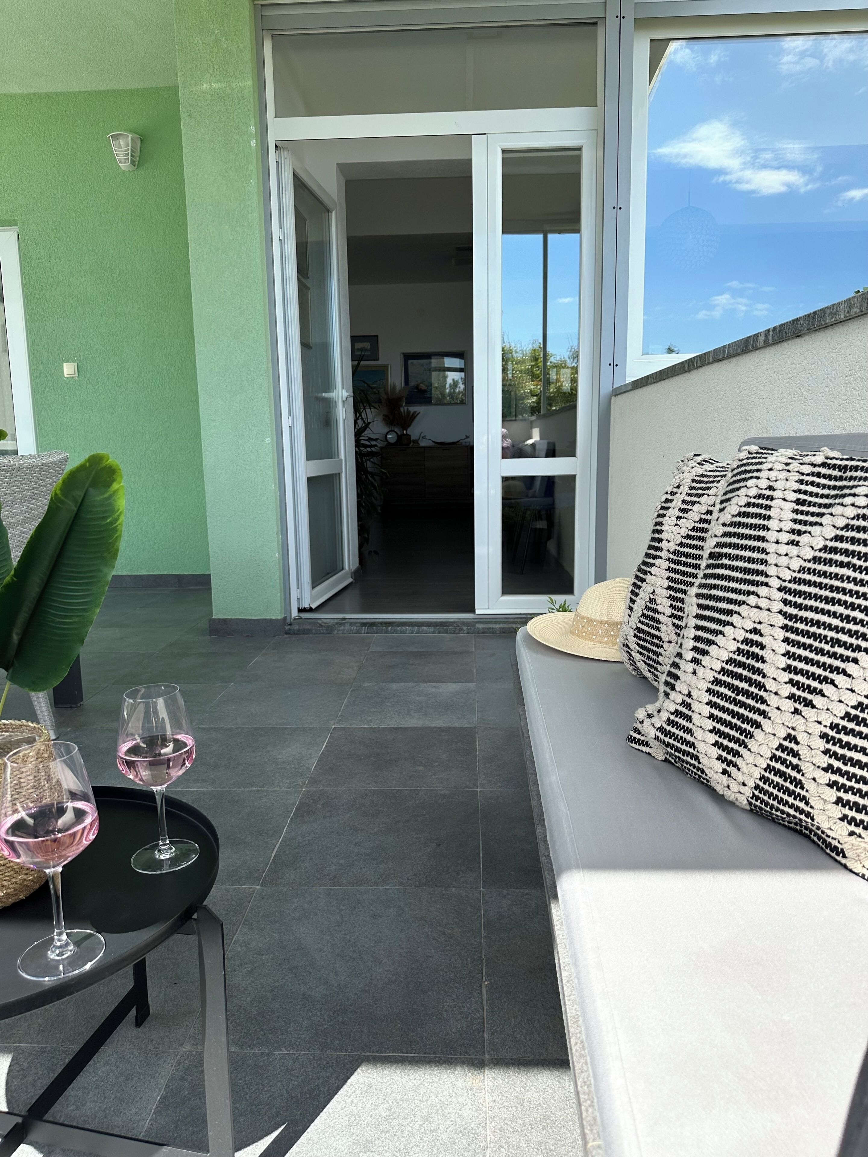 A balcony with a sofa, two wine glasses, and a table.
