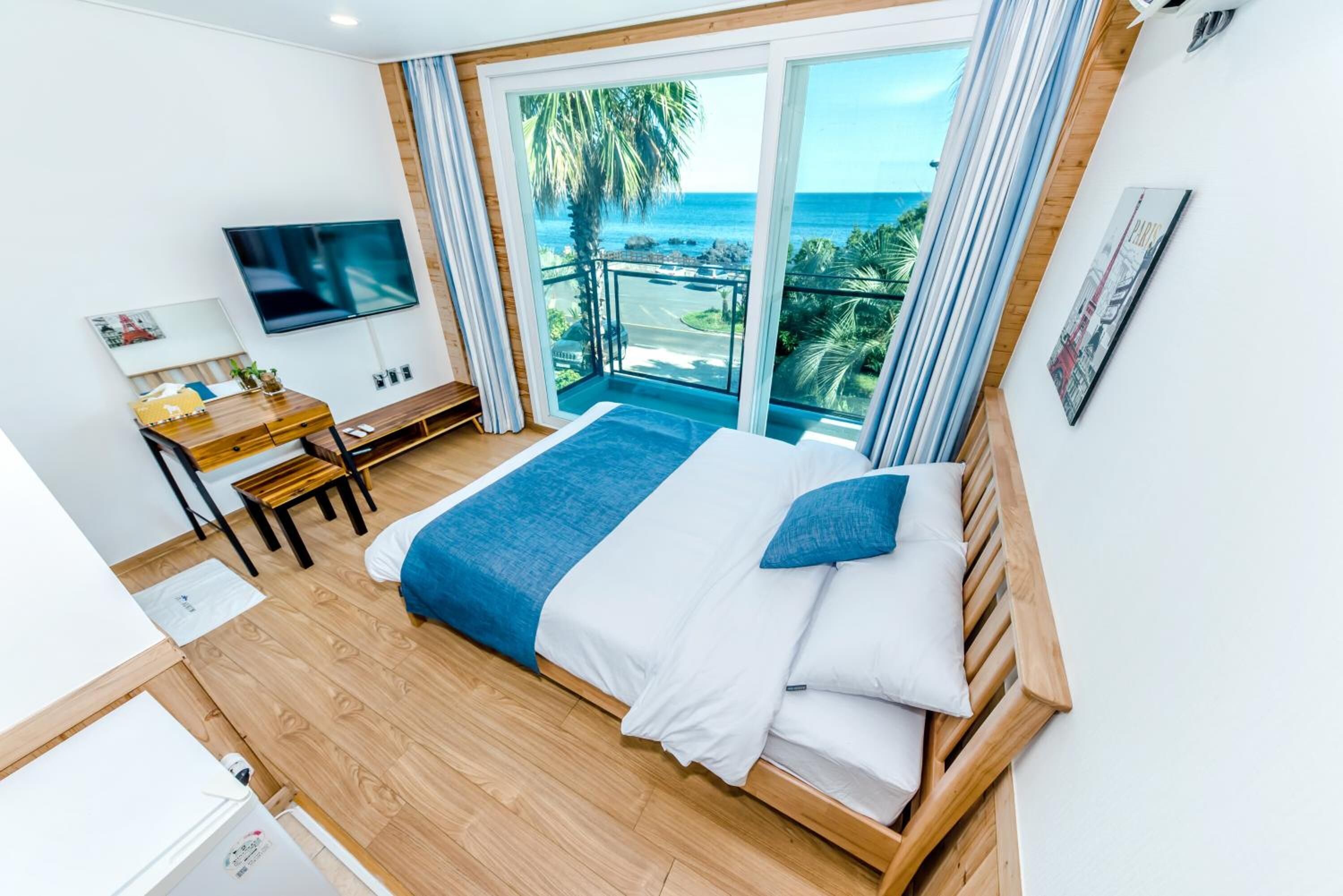 Une chambre avec un lit, un bureau, une télévision et un balcon donnant sur l’océan.