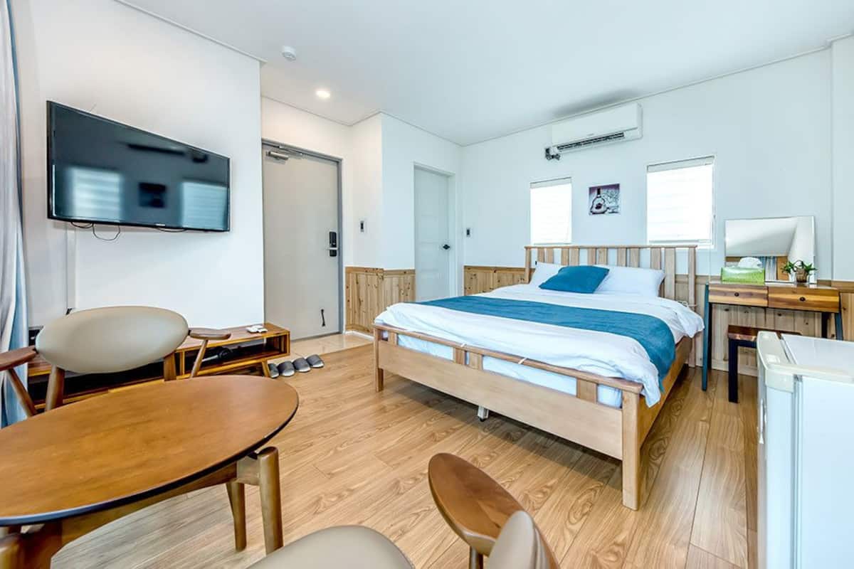 A hotel room with a bed, a desk, a chair, a TV, and a window.