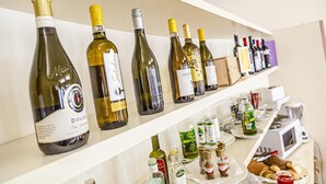 Una estantería para vinos con varias botellas y una barra con salsas y aperitivos.