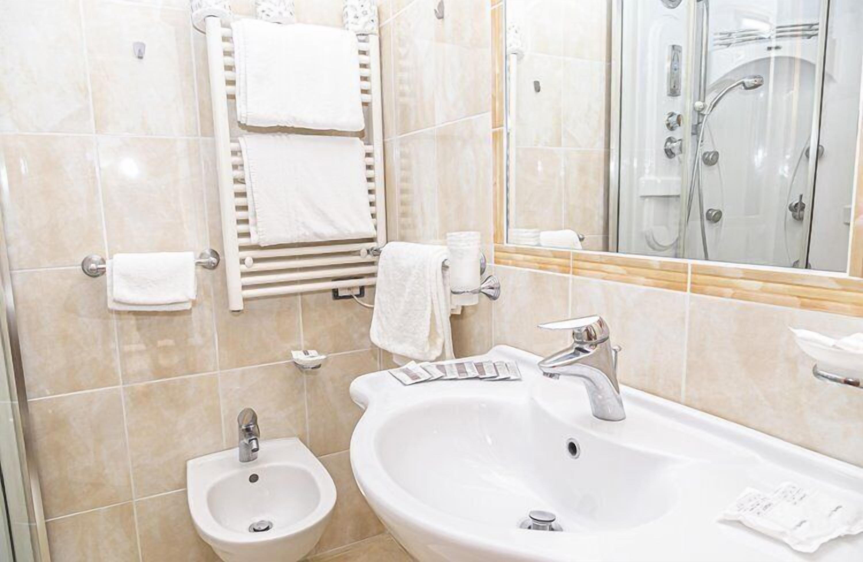 Un baño moderno con un lavabo grande, bidé, toallero y zona de ducha con mampara de cristal.
