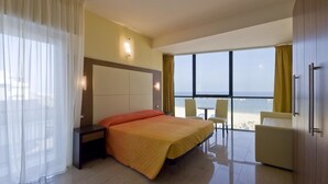 Habitación de hotel con cama, escritorio, silla y vista a la playa.