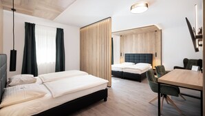 A hotel room with a bed, a desk, a chair, a TV, and a window with curtains.