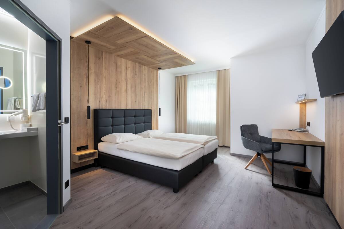 A modern bedroom with a bed, a desk, and a TV.